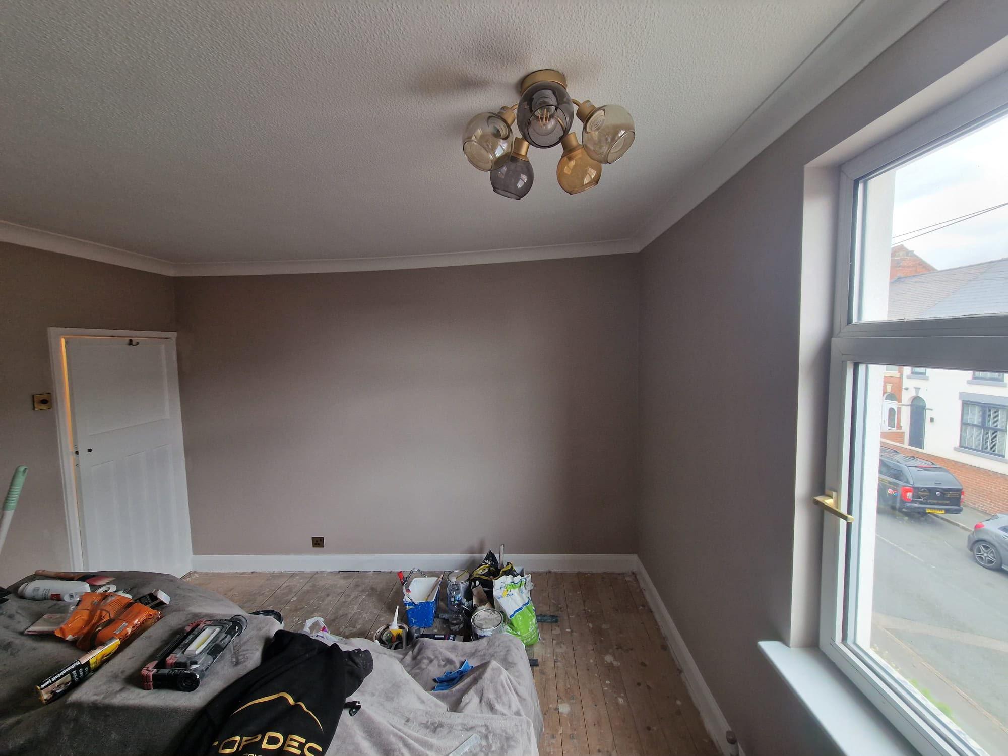 Bedroom painted warm mushroom with a white ceiling, coving and door, and a bay window