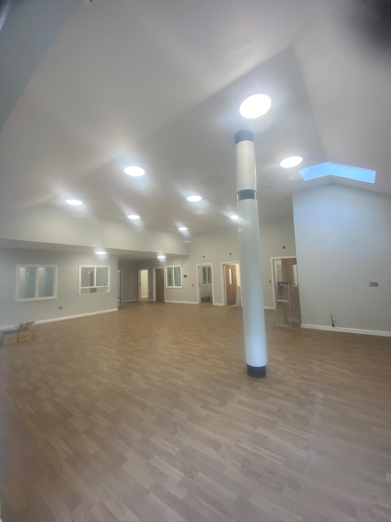 Large community hall two storeys high with a white vaulted ceiling and pale grey walls