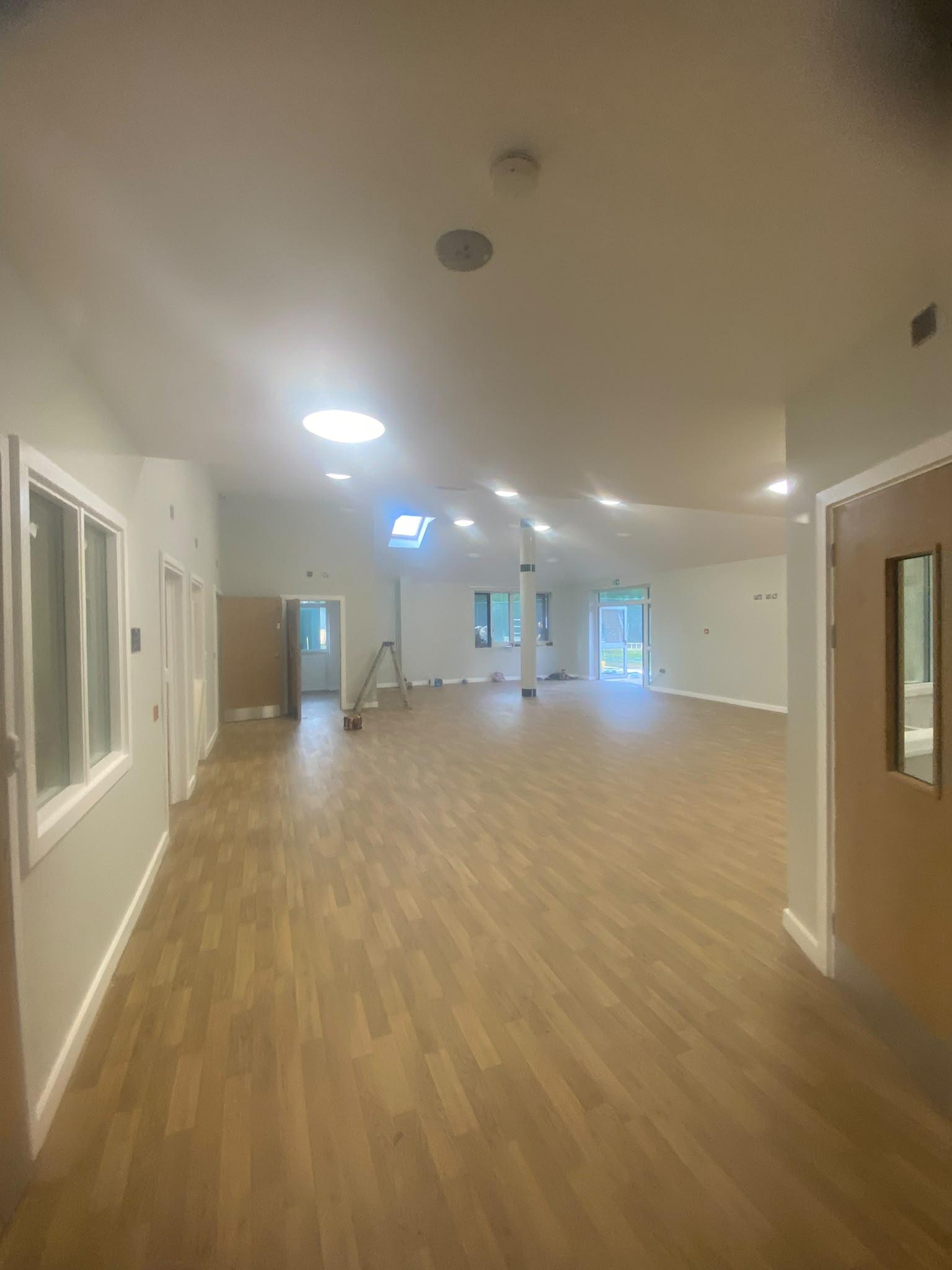 Commercial corridor and hall with warm white walls, oak fire doors and vinyl flooring