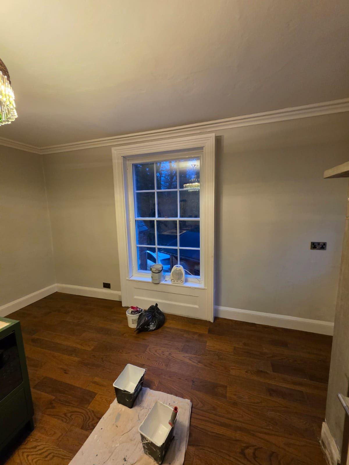 Period sash window with a panelled reveal and architrave painted white against warm grey walls