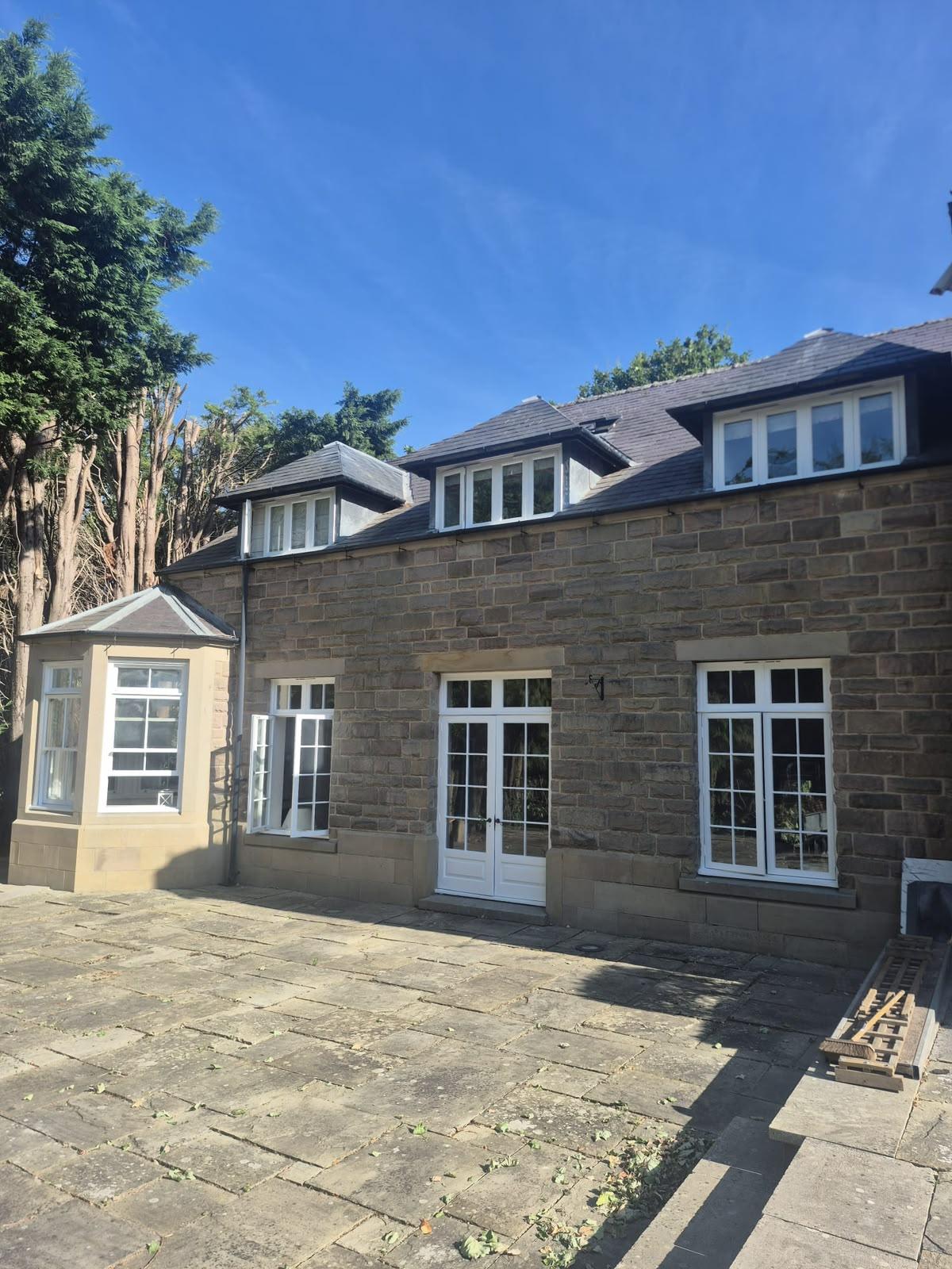 Stone house with slate dormers and freshly painted white timber windows and French doors