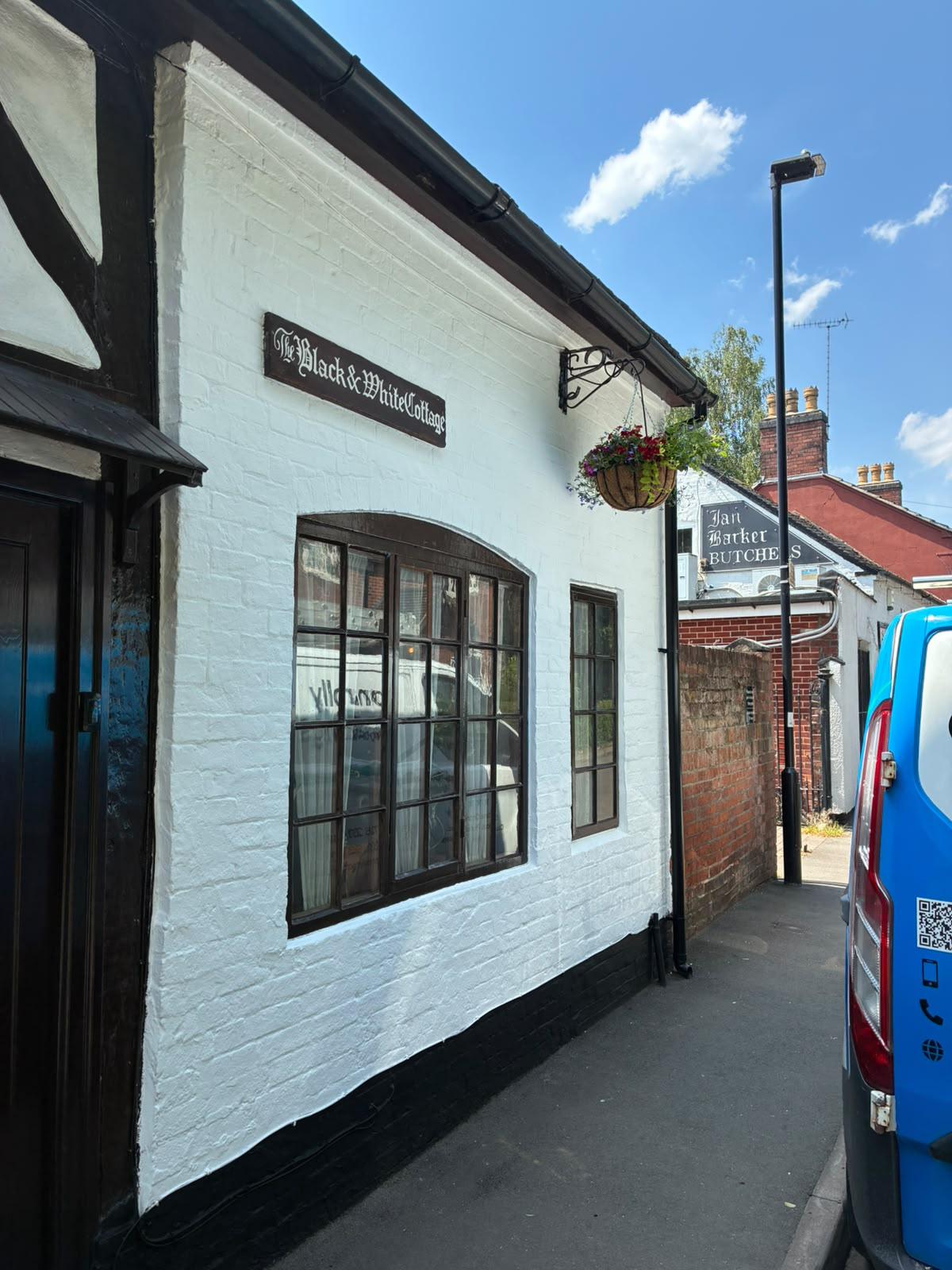 White painted timber framed cottage with black beams and window frames, named The Black and White Cottage