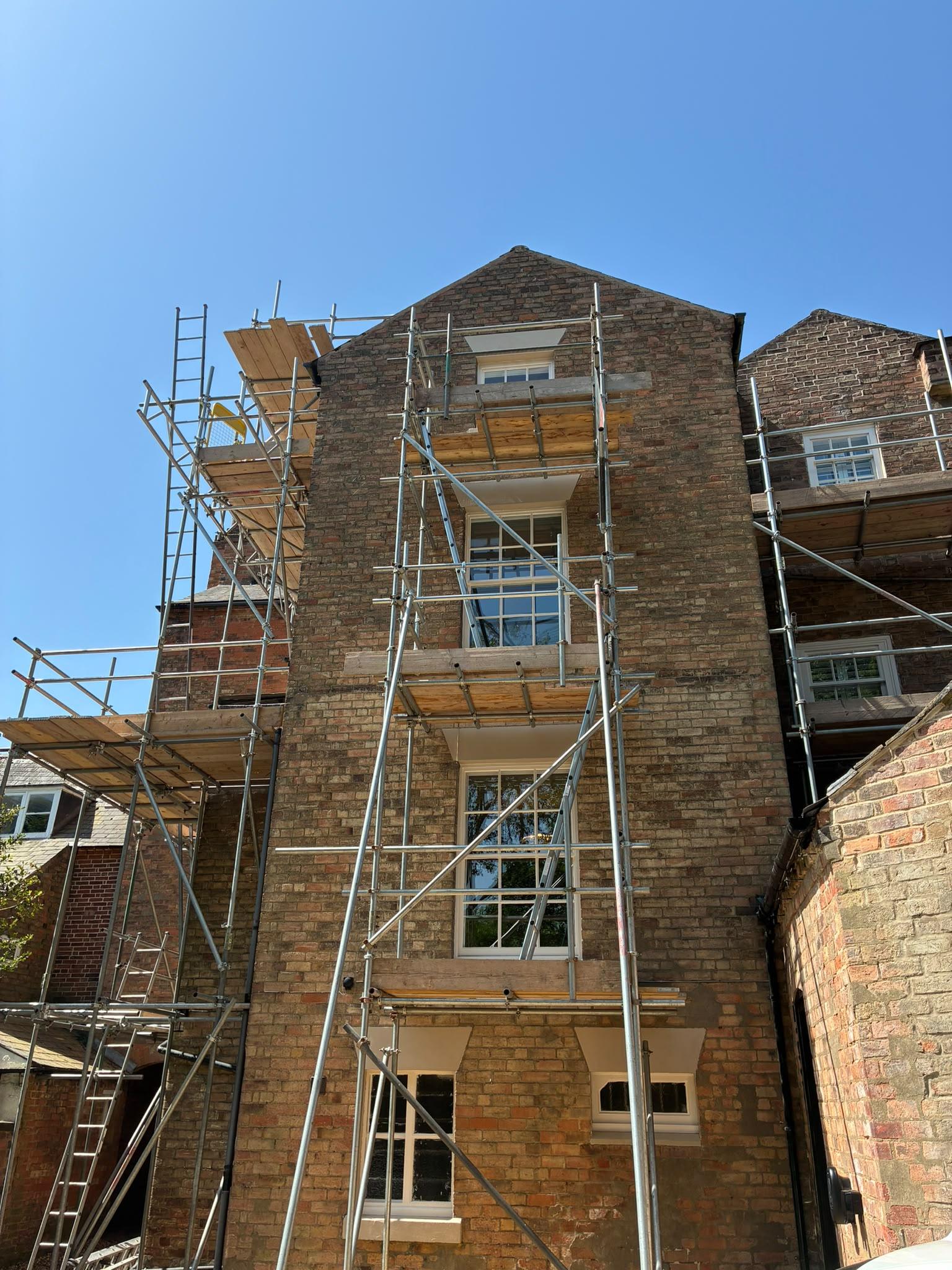 Scaffolding on a three storey Georgian brick building with freshly painted cream sash windows