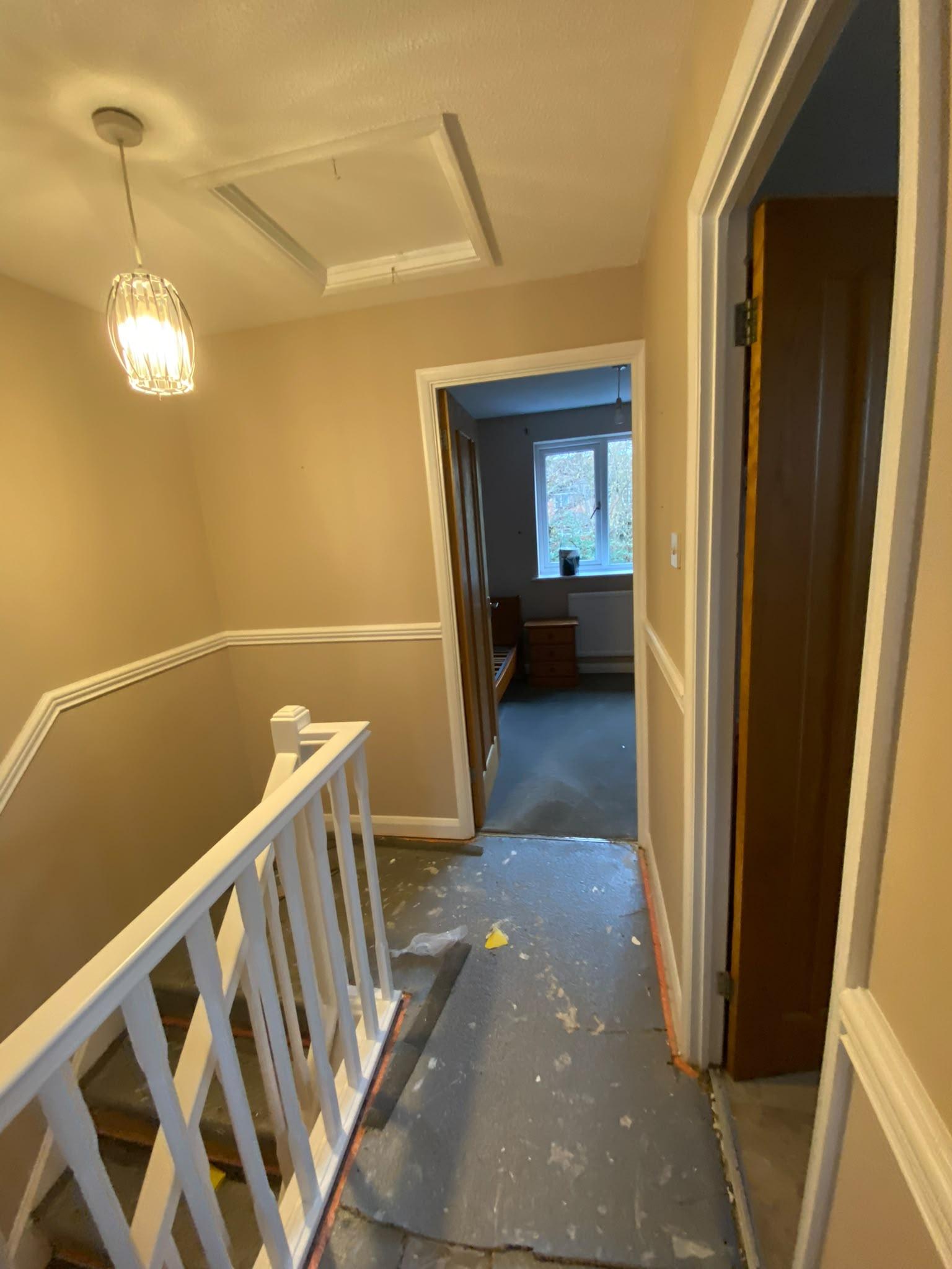 Upstairs landing painted soft yellow with a white dado rail and staircase spindles