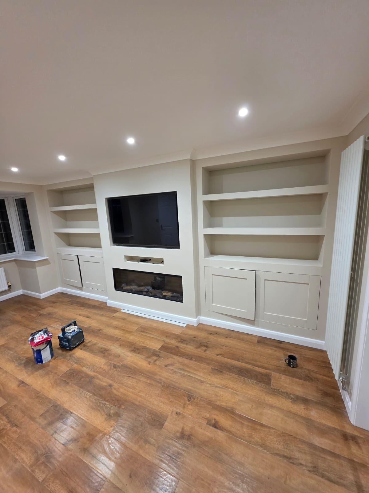Bespoke white media wall with floating shelves, an inset electric fire and a recessed TV