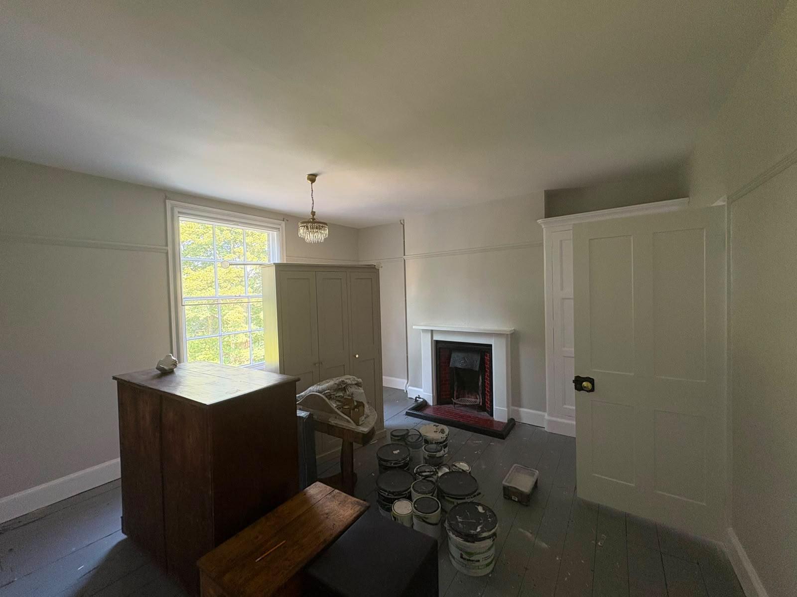 Period living room painted sage green with a white marble fireplace and panelled door