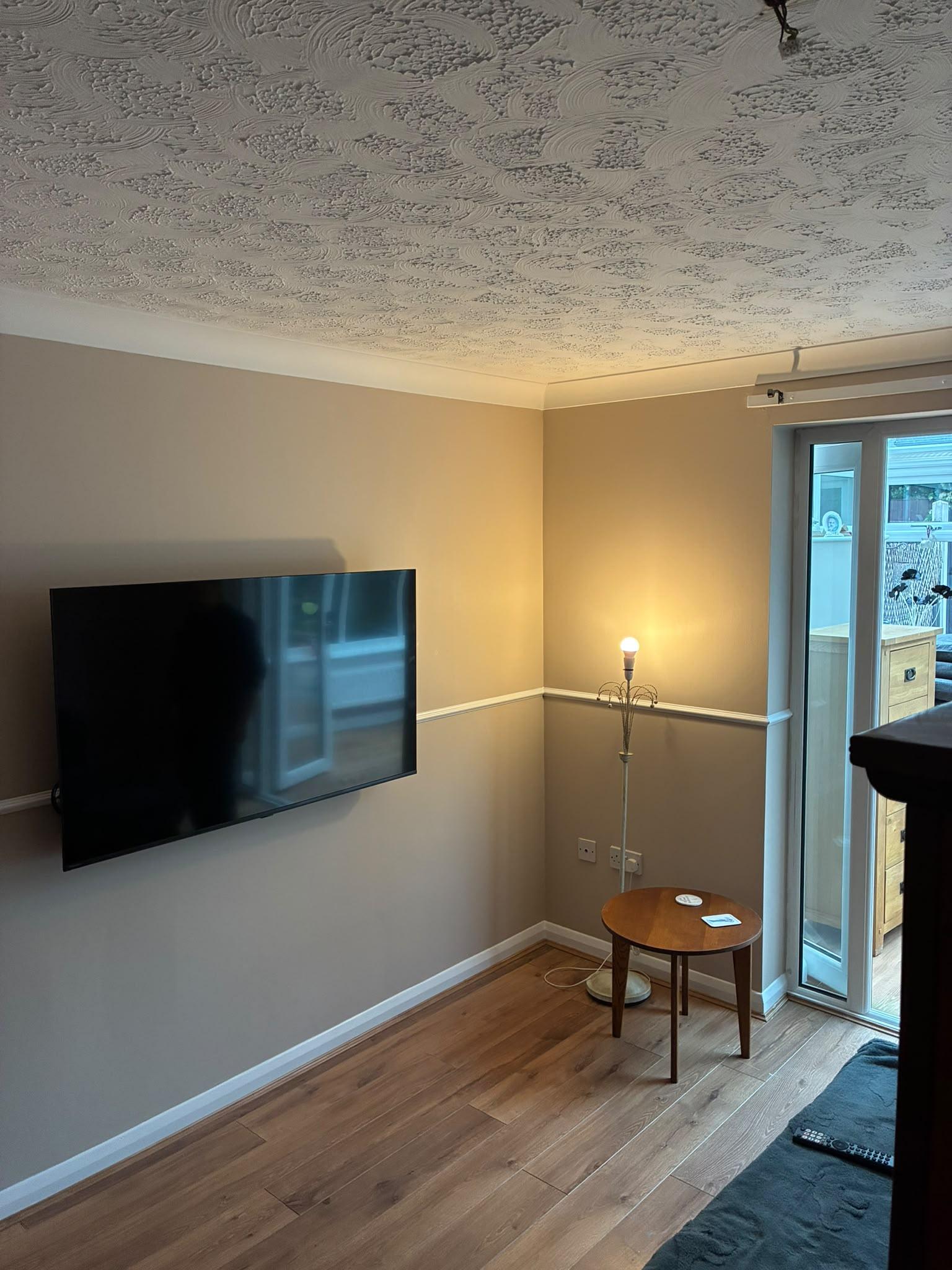 Living room painted warm caramel with a white dado rail and skirting, and a wall mounted TV
