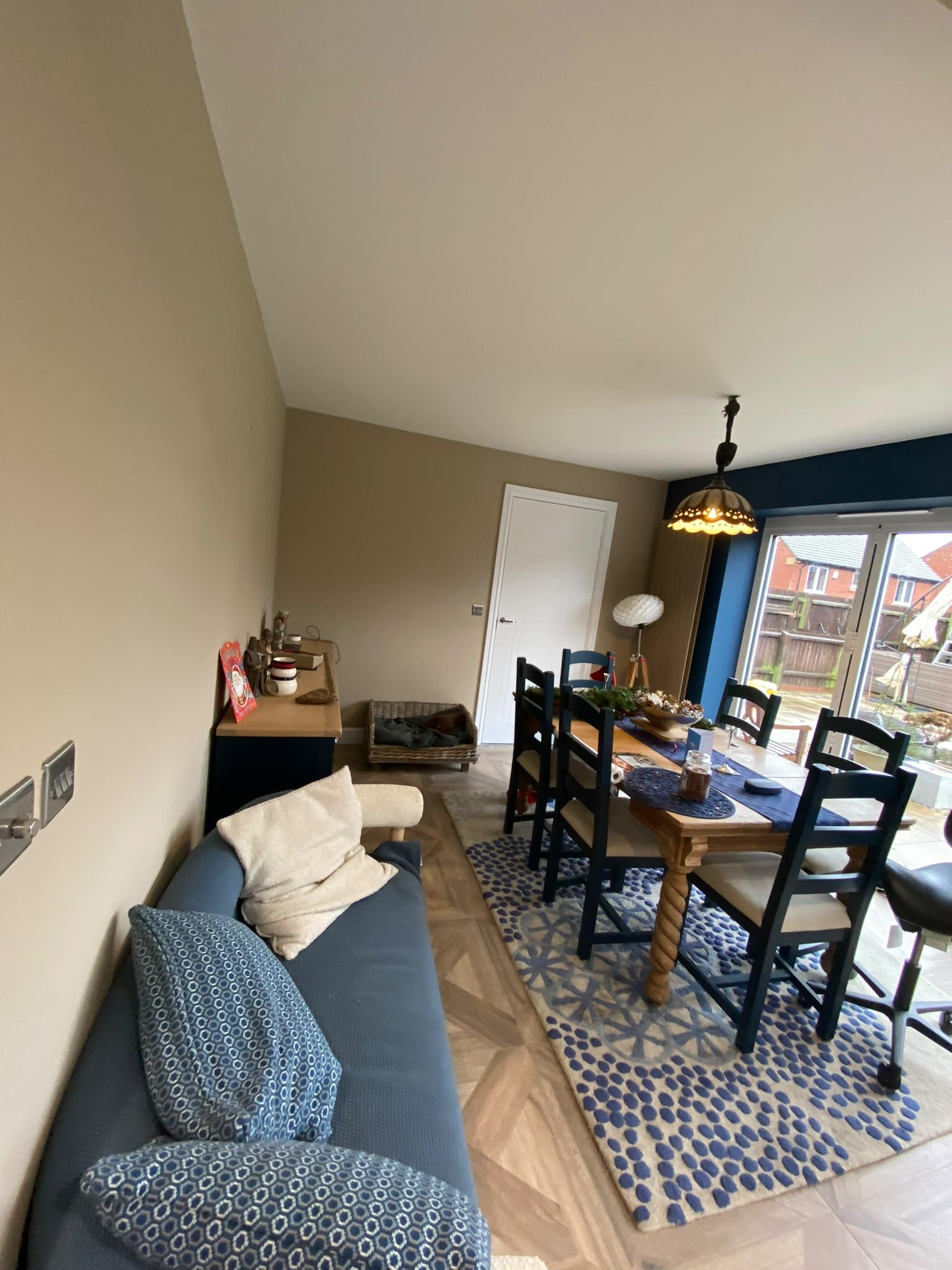 Open plan dining area painted taupe with a navy feature wall around the patio doors